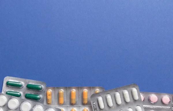 Farklı ilaçlar: tabletler, su toplayan haplar, mavi arka planda ilaçlar. Yakın plan fotoğraf, fotokopi alanı, üst görüntü. Yüksek kalite fotoğraf