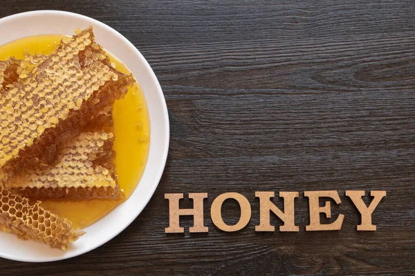 木製のテーブルの上に白いプレートにハニカム 天然の有機蜂製品 健康的なライフスタイル 言葉の蜂蜜 テキストのスペースをコピーします 高品質の写真 — ストック写真