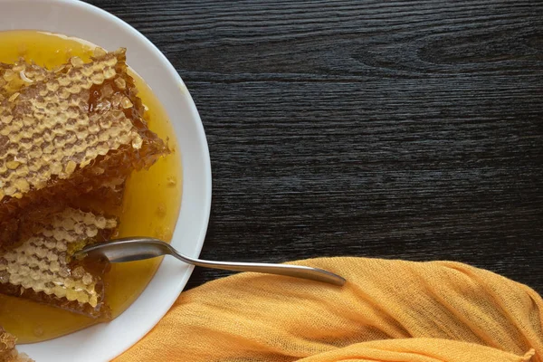 Honeycombs med sked i vit platta på träbordet. Naturlig ekologisk biprodukt. En hälsosam livsstil. Kopiera utrymme för din text — Stockfoto