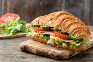 Peynir, jambon ve ahşap masa sebze ile kruvasan sandviç