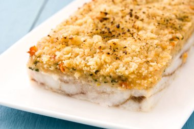 Mavi ahşap zemin üzerine peynir ile beyaz balık güveç.