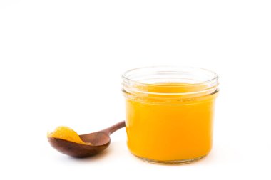 Ghee veya kavanoz ve tahta kaşık beyaz arka plan üzerinde izole eritilmiş tereyağı
