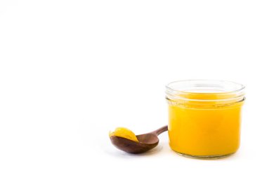 Ghee veya kavanoz ve tahta kaşık beyaz arka plan üzerinde izole açıklık tereyağı. Boşaltmak