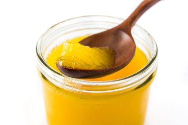 Ghee veya kavanoz ve tahta kaşık beyaz arka plan üzerinde izole eritilmiş tereyağı