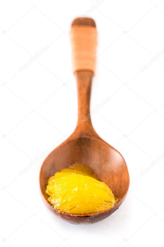 Ghee or clarified butter in wooden spoon isolated on white background. 