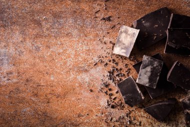 Kahverengi zemin üzerine siyah çikolata parçaları. Üstten görünüm tasarlamak