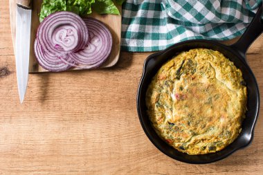 Yumurta ve ahşap masa üzerinde bir Demir Tavada sebze frittata yapmış. Üstten görünüm. Boşaltmak