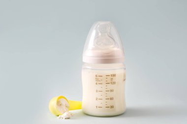 Biberon ve gri arka plan üzerinde süt