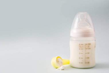 Biberon ve gri arka plan üzerinde süt. Boşaltmak