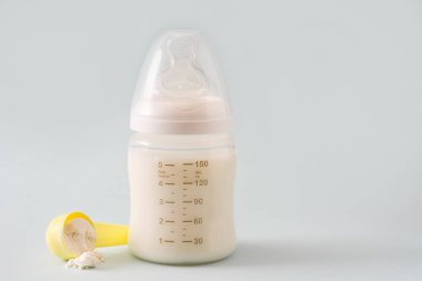 Biberon ve gri arka plan üzerinde süt. Boşaltmak