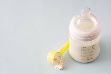 Biberon ve gri arka plan üzerinde süt. Boşaltmak