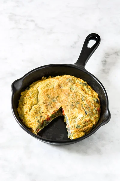 Yumurta ve beyaz mermer üzerinde bir Demir Tavada sebze frittata yapılmış