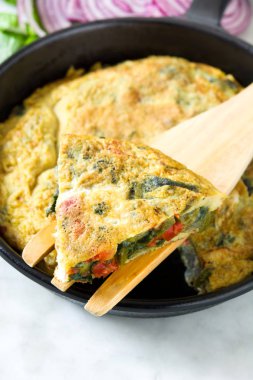 Yumurta ve beyaz mermer üzerinde bir Demir Tavada sebze frittata yapılmış