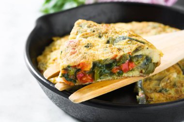 Yumurta ve beyaz mermer üzerinde bir Demir Tavada sebze frittata yapılmış