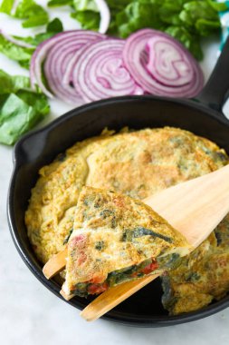 Yumurta ve beyaz mermer üzerinde bir Demir Tavada sebze frittata yapılmış