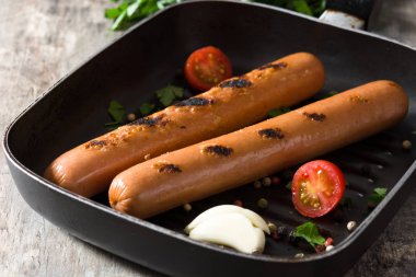 Ahşap masa üzerinde demir tavada ızgara sosis