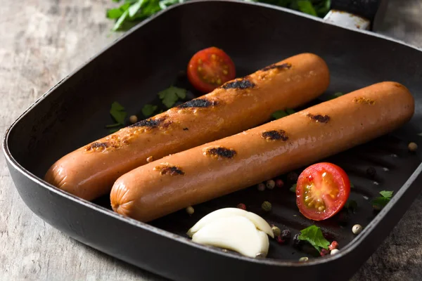 Ahşap masa üzerinde demir tavada ızgara sosis