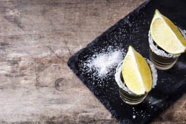 Limon ve tuz ahşap masa üzerinde altın Meksika tekila. Üstten görünüm. Boşaltmak