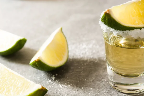 Mexican Gold tequila with lime and salt on gray background