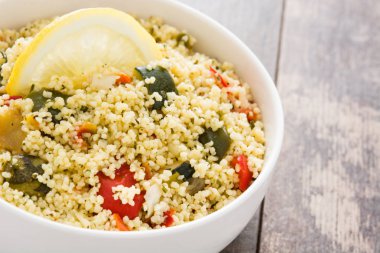 Ahşap masa üzerinde bir kapta sebzeli kuskus. 