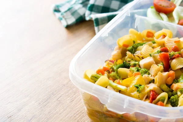 Healthy meal prep containers with food ready to eat. Pasta salad on wooden table. Copyspace