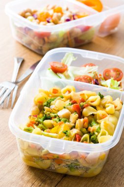 Sağlıklı yemek hazırlık kapları ile yemek yemeye hazır. Ahşap masa üzerinde makarna salatası. Boşaltmak