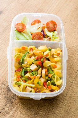 Sağlıklı yemek hazırlık kapları ile yemek yemeye hazır. Ahşap masa üzerinde makarna salatası. Boşaltmak