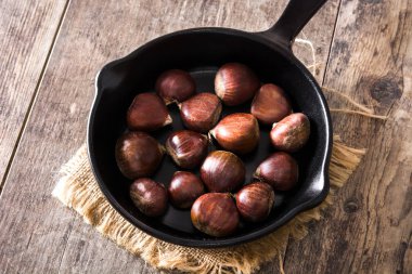 Ahşap masa üzerinde demir tavada kestane