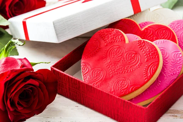 白い木製のテーブルにバレンタインの日に薔薇をあしらったギフト ボックスにハートのクッキー — ストック写真