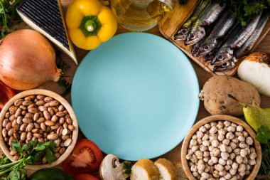 Healthy eating. Mediterranean diet. Fruit,vegetables, grain, nuts olive oil and fish on wooden table. Top view with copy space on plate clipart