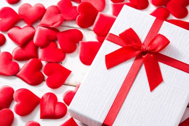 Beyaz ahşap zemin üzerinde kırmızı kalpler ve Hediyelik kutu. Boşaltmak