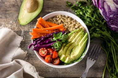 Vegan Buda kase taze çiğ sebze ve ahşap masa üzerinde quinoa ile. Üstten görünüm. 