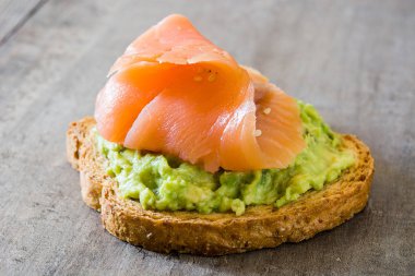 Ahşap masa üzerinde taze somon ile avokado tost kapatın
