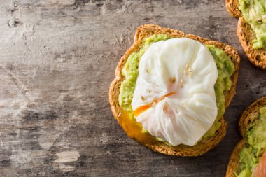 Ahşap masa haşlanmış yumurta ile avokado tost kapatın. Üstten görünüm. Boşaltmak