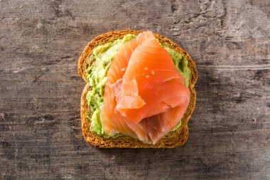 Ahşap masa üzerinde taze somon ile avokado tost kapatın. Üstten görünüm