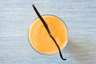 Mavi zemin üzerine ev yapımı vanilyalı muhallebi kase. Üstten görünüm