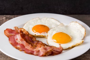 Kızarmış yumurta ve domuz pastırması ahşap masa günü kahvaltıda. Yakın çekim