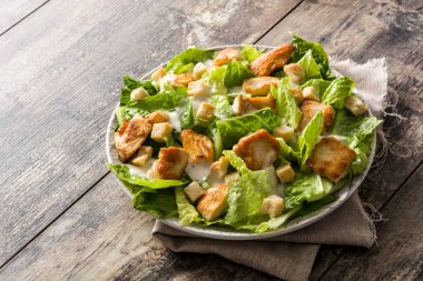 Sezar salatası marul, tavuk ve kruton ahşap tablo.