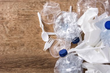 Ahşap arka planda tek kullanımlık atık plastik. Üst görünüm. Boşaltmak