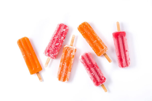 Orange and strawberry popsicles isolated on white background. Top view