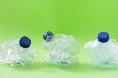 Yeşil arka planda tek kullanımlık atık plastik şişeler