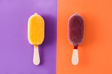 Menekşe ve turuncu arka planda çilek ve turuncu buzlu şekerler.