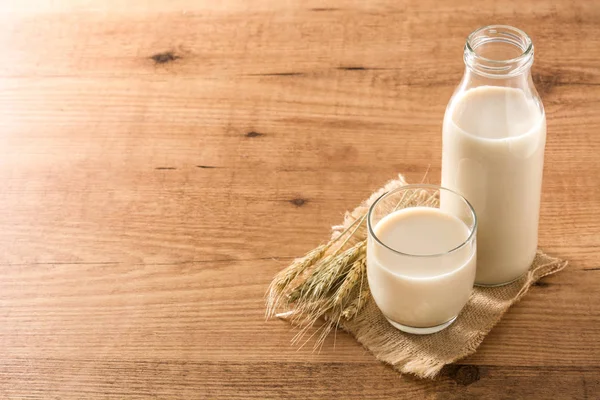 Yulaf sütü şişede ve cam ahşap masada. Copyspace