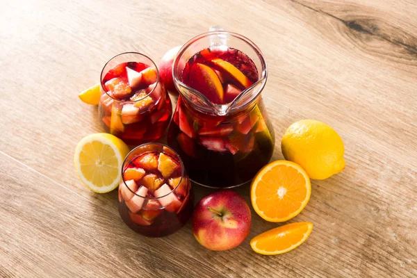 Red wine sangria in glasses on wooden table.