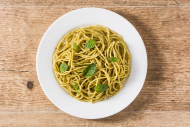 Ahşap masada pesto soslu spagetti makarna. Üstte görüntü