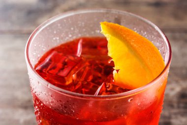 Ahşap masa üzerinde cam turuncu parçası ile Negroni kokteyl. Yakın çekim