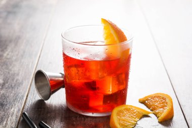 Ahşap masa üzerinde cam turuncu parçası ile Negroni kokteyl. 