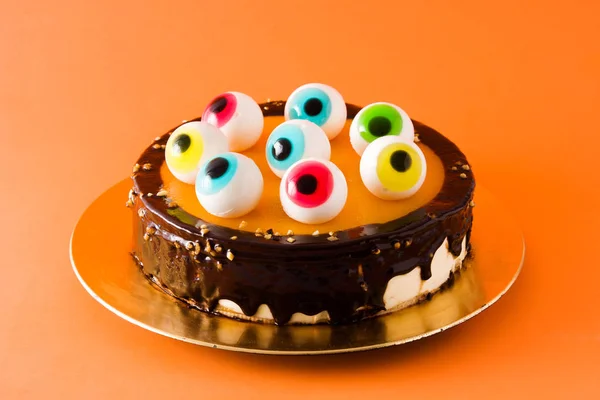 Halloween cake with candy eyes decoration on orange background