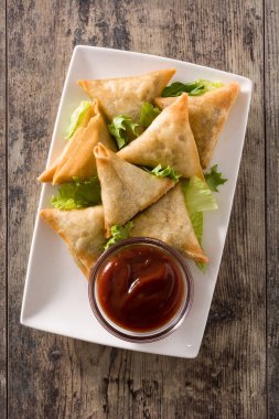 Samsa veya samosas ahşap masada et ve sebze ile. Geleneksel Hint yemekleri. Üstte görüntü.