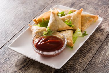 Samsa veya samosas ahşap masada et ve sebze ile. Geleneksel Hint yemekleri. 